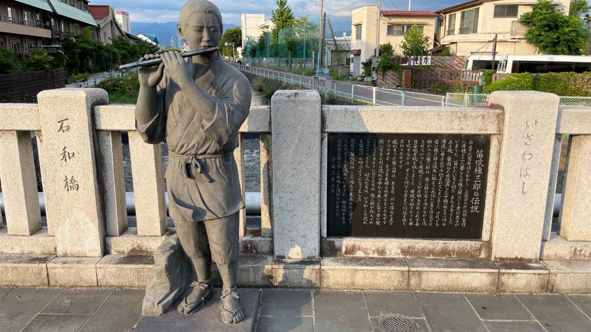 石和橋のたもとに立つ笛吹権三郎の像