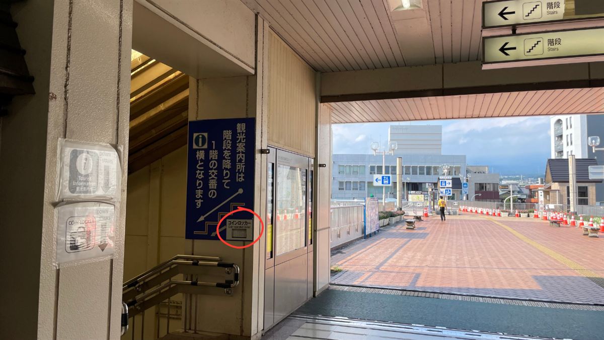 富士宮駅の「観光案内所は階段を降りて1階の交番の横となります」の案内板と、その下の小さなコインロッカー表示