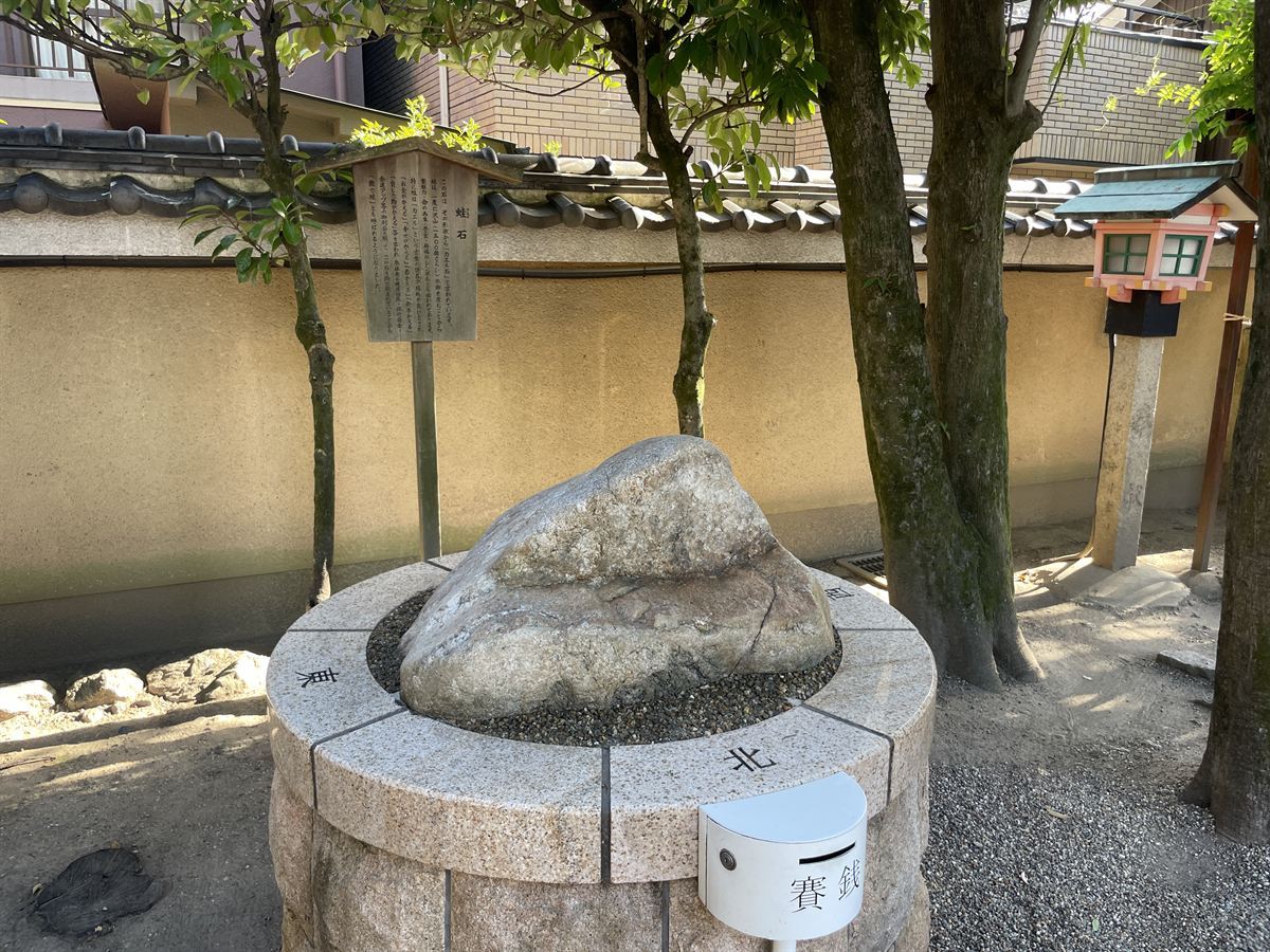 率川神社の蛙石。丸い台座の上に置かれた、カエルの形に見える石