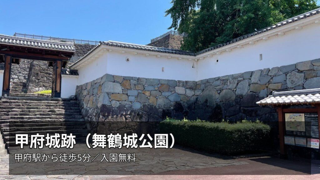 甲府城跡（舞鶴城公園）の門と石垣、白漆喰の塀。「甲府城跡（舞鶴城公園）／甲府駅から徒歩5分／入園無料」の文字入り