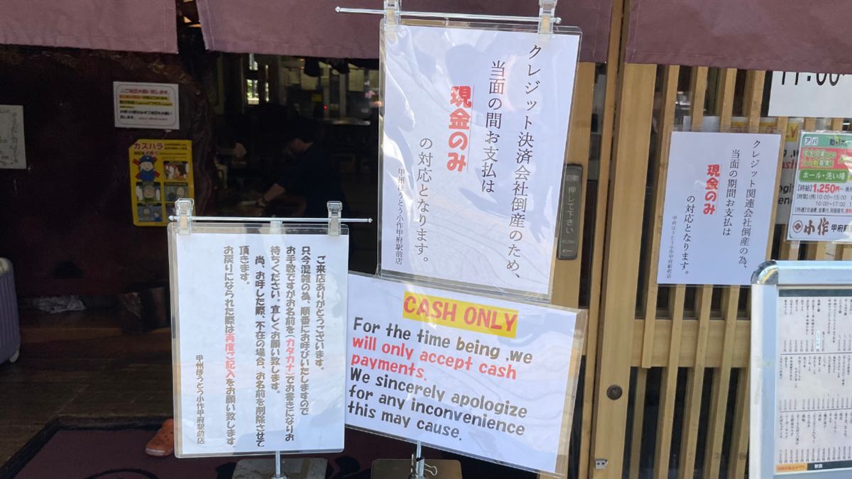 小作 甲府駅前店の入口に並ぶ掲示。「当面の間お支払は現金のみの対応となります」と「CASH ONLY」の貼り紙