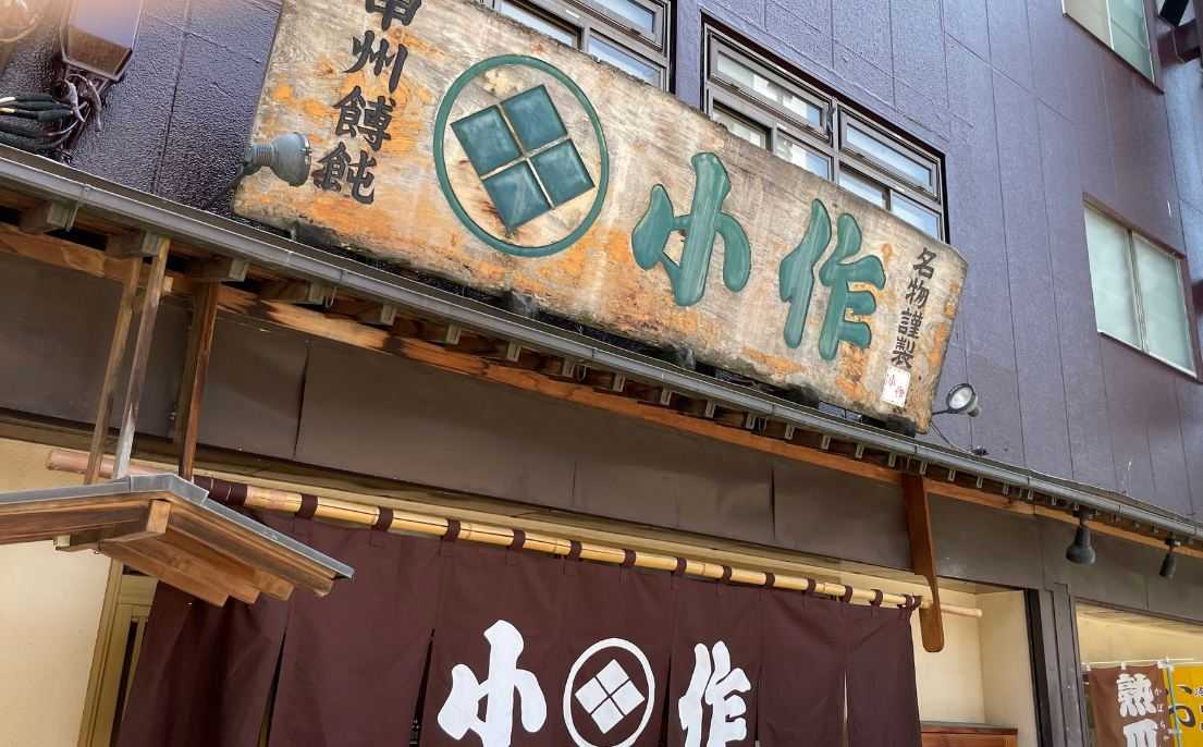 甲州ほうとう小作 甲府駅前店の外観。武田菱の紋が入った古い木の看板と、店名の入った暖簾