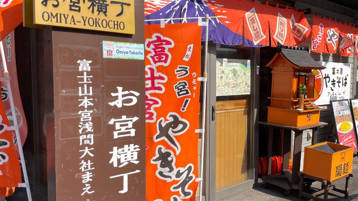 「お宮横丁 OMIYA-YOKOCHO」の看板と、「蒸し麺」「削り粉」「肉かす」と書かれた赤い幟が並ぶ入口