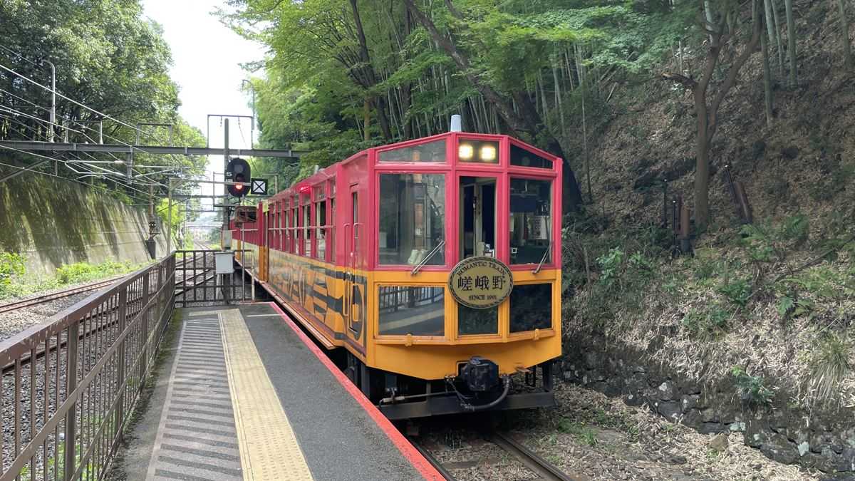 トロッコ嵐山駅に停車する嵯峨野トロッコ列車。赤と黄の車体にROMANTIC TRAINのヘッドマーク