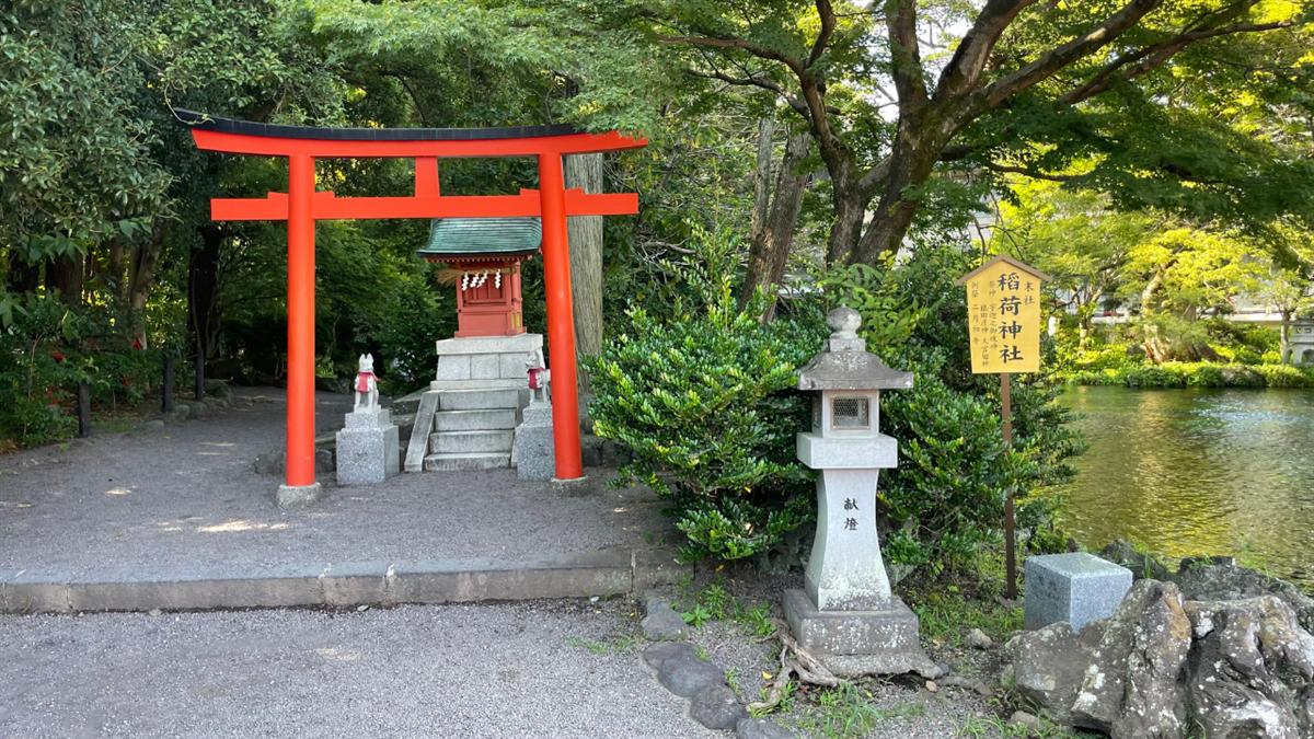 湧玉池のほとりに立つ稲荷神社の朱塗りの鳥居と小さな社殿