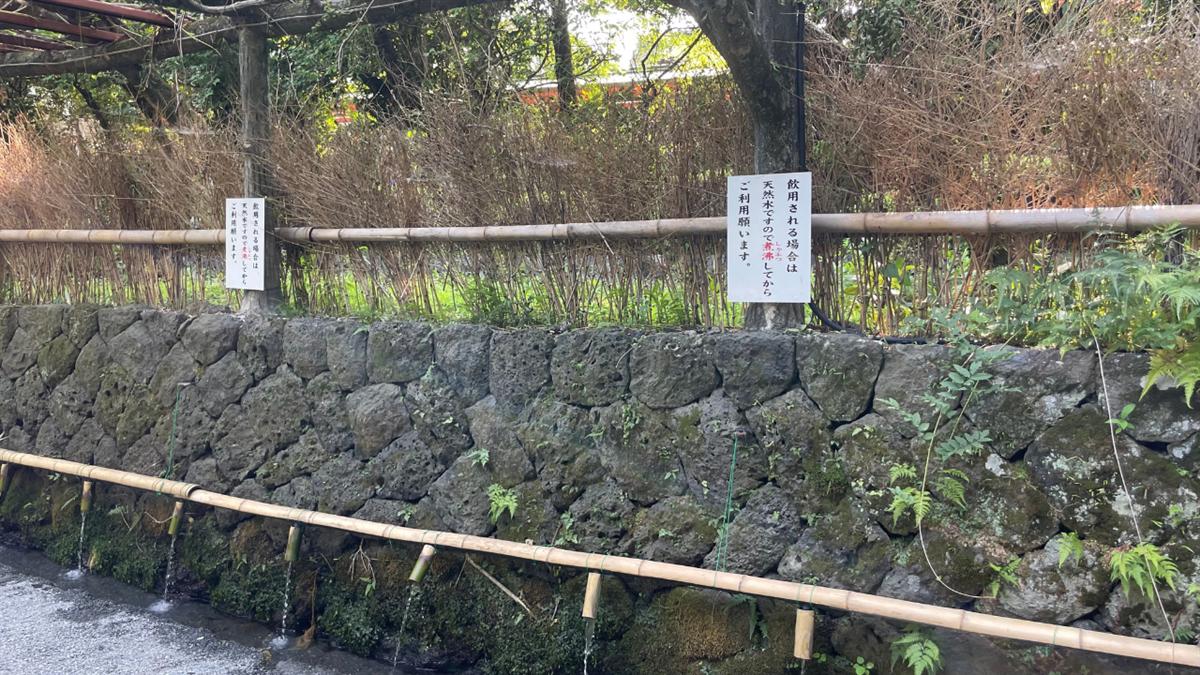 竹樋から水が流れ出る水取場と、「飲用される場合は煮沸してからご利用願います」の掲示