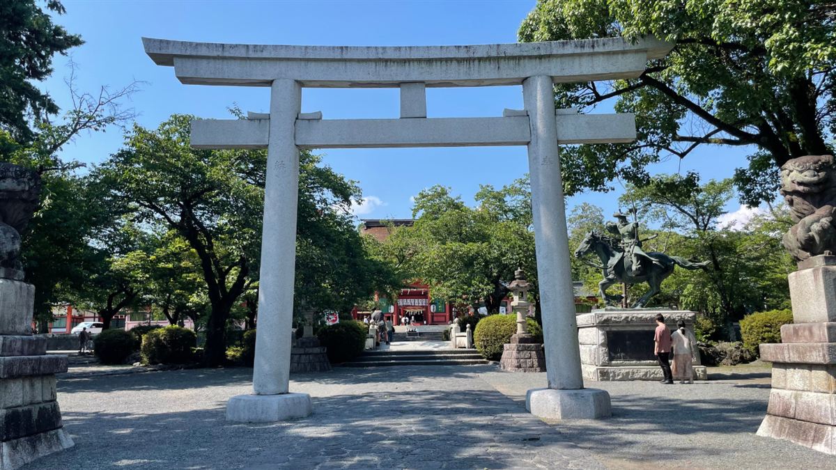 石造りの大鳥居越しに見る富士山本宮浅間大社の参道と、右手の流鏑馬の騎馬像