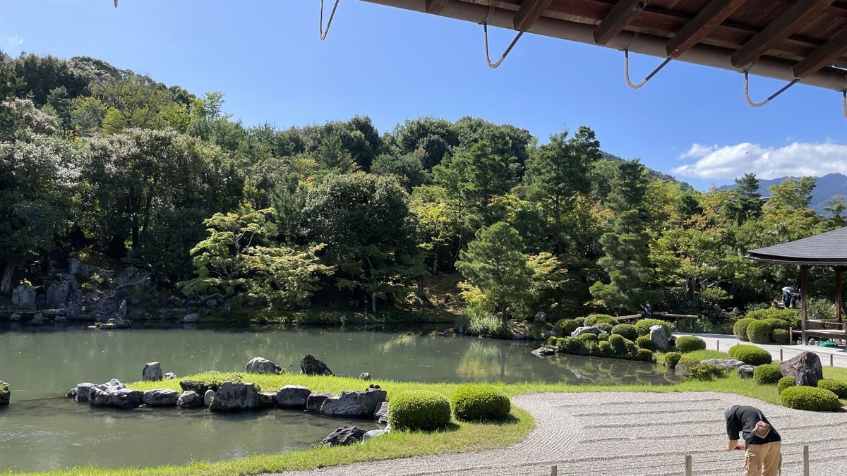 本堂の軒下から見た曹源池庭園。手前に白砂の砂紋、奥に池と嵐山の借景