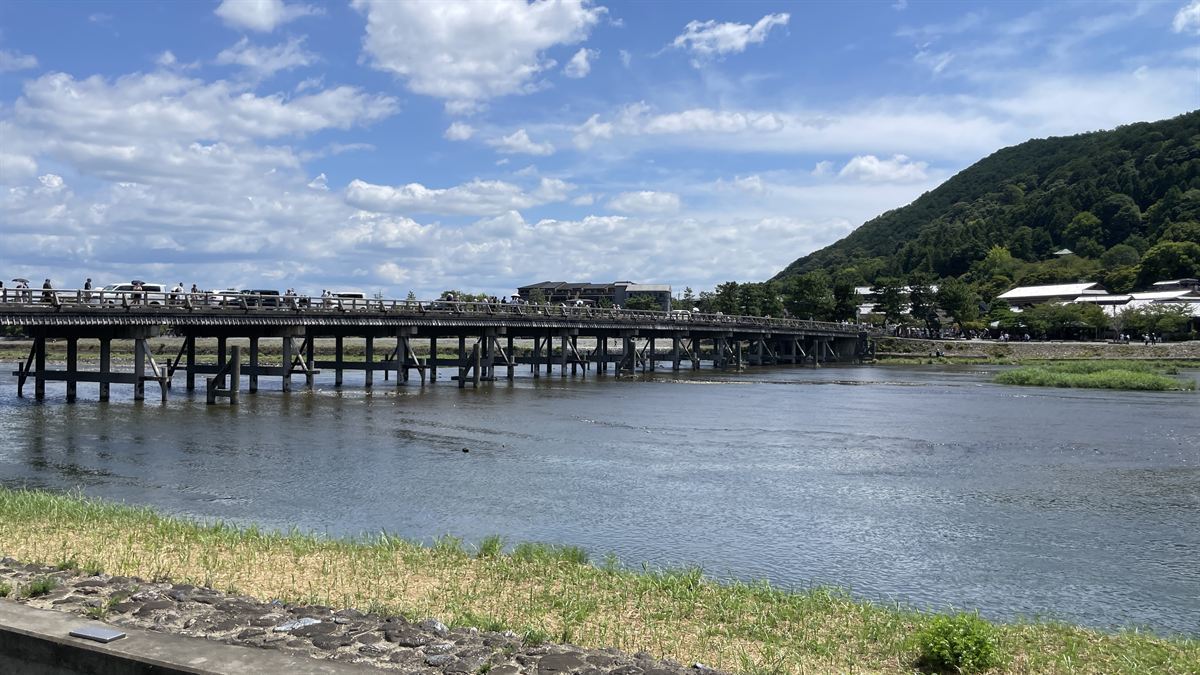 午後の渡月橋。青空の下、橋の上に多くの人が歩いている