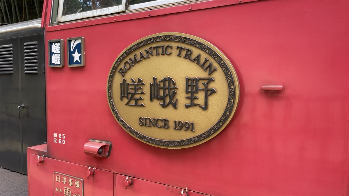 嵯峨野トロッコ列車の車体エンブレム。「ROMANTIC TRAIN 嵯峨野 SINCE 1991」と金色で記されている