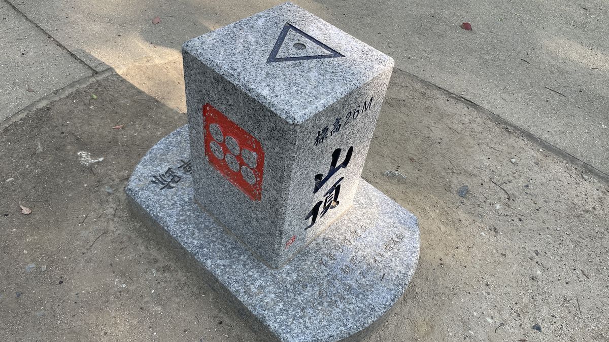 茶臼山の山頂の標石の別の面。赤い六文銭の紋と「山頂 標高26M」の文字が刻まれている