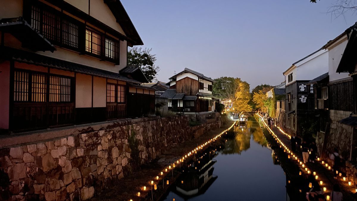 日が暮れたあとの八幡堀。両側の石垣に沿って小さな灯りが並び、古い町家と蔵が続いている