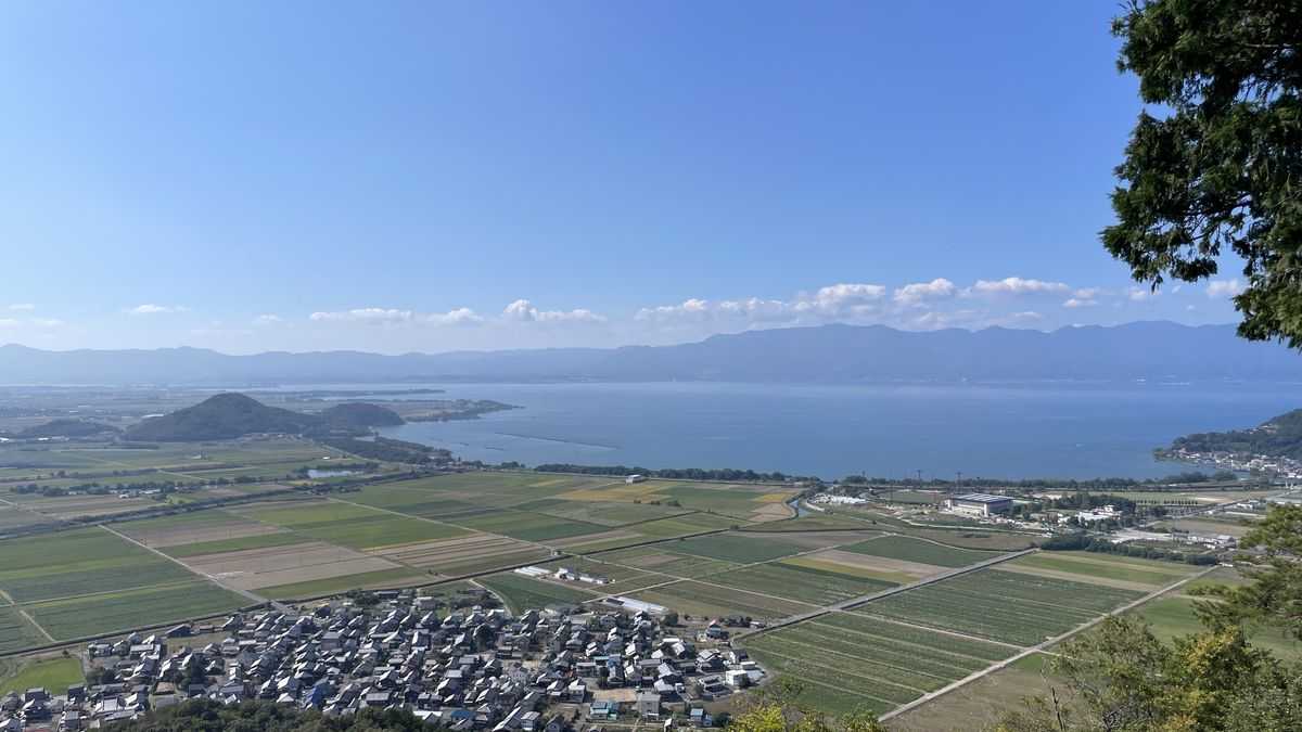 八幡山の山頂から見た眺め。手前に家並みと田んぼが広がり、奥に琵琶湖と山なみが見えている