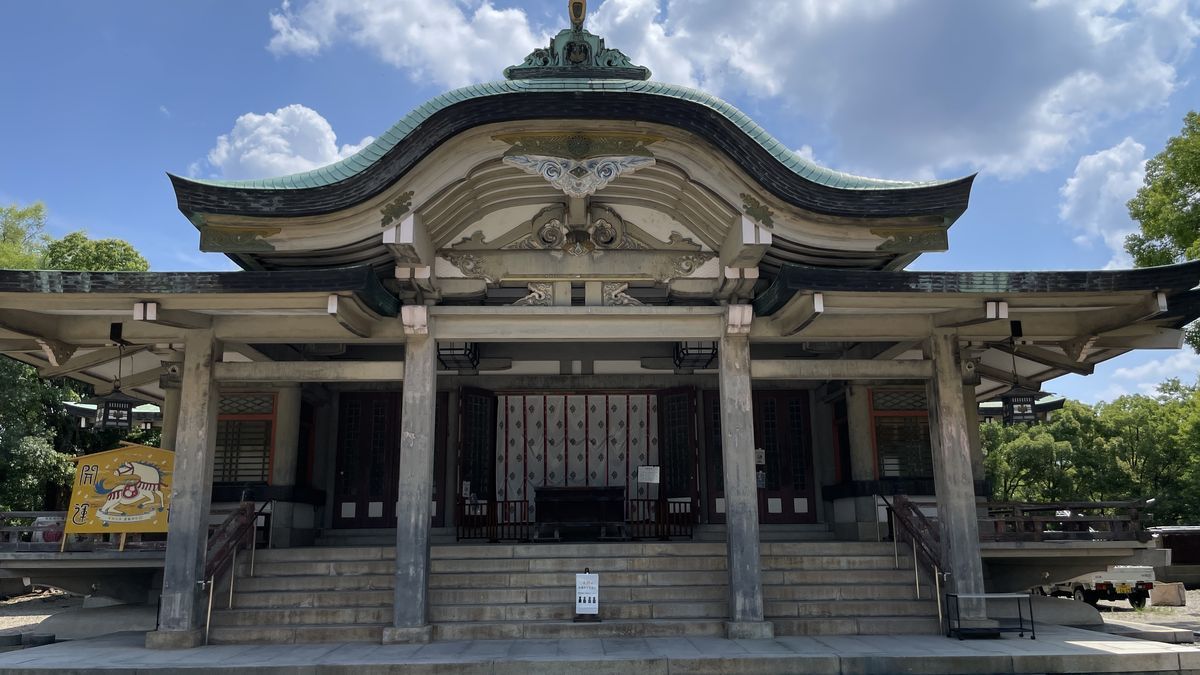 豊國神社の拝殿を正面から見た様子。緑青色の反った屋根の下に石段があり、奥に白い幕が掛かっている
