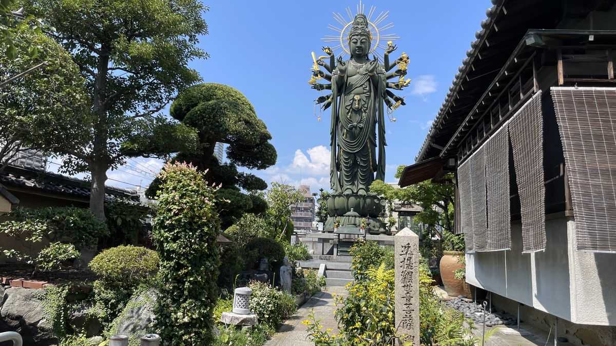興徳寺の大きな観音像。腕がたくさんある観音像が、庭の木々の奥に立っている