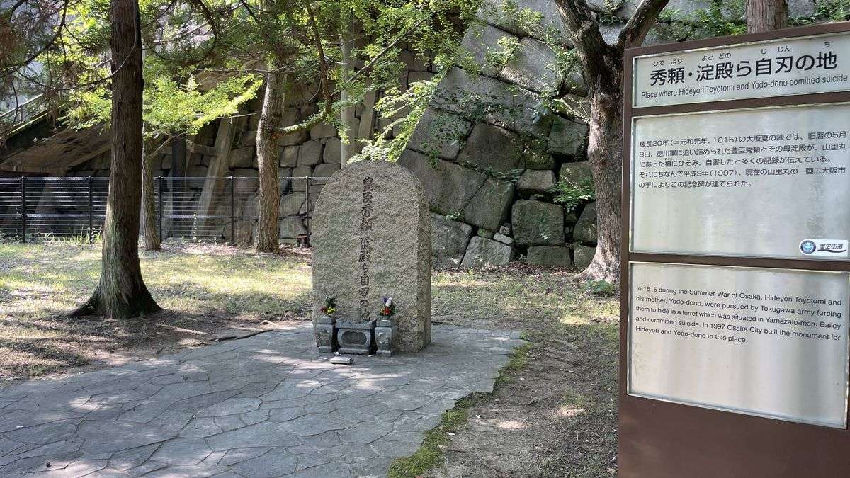 大阪城 山里丸にある「豊臣秀頼 淀殿ら自刃の地」の石碑。碑の前に花が供えられ、右側に説明板が立っている