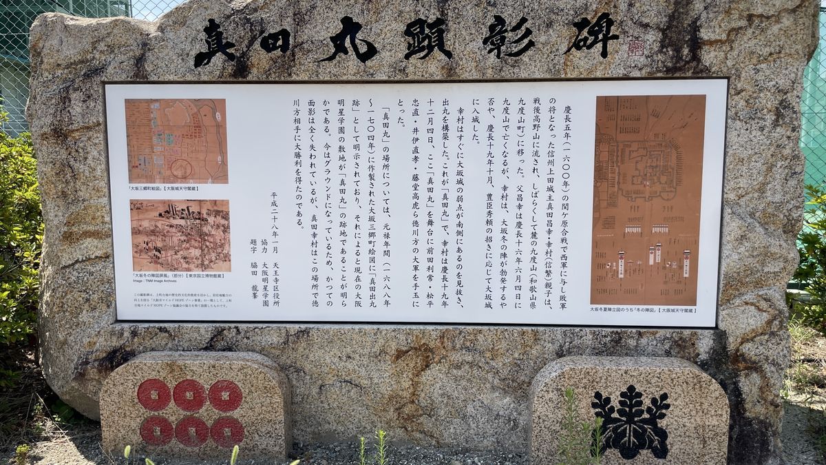 真田丸顕彰碑。「真田丸顕彰碑」の題字の下に古地図と解説の陶板があり、足元に六文銭と桐の紋の石がある