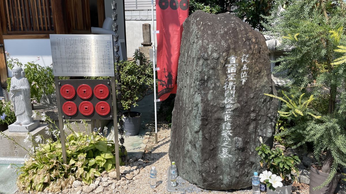 心眼寺の墓碑。大きな自然石に「従五位下 真田左衛門佐豊臣信繁之墓」と刻まれ、左に六文銭の飾りと説明板がある
