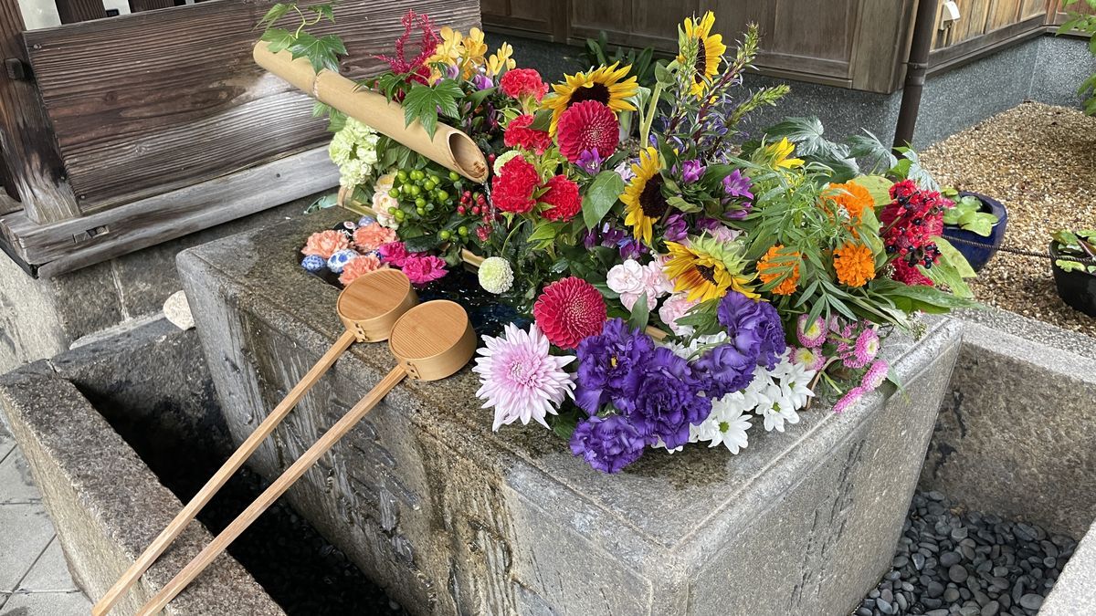 勝林寺の花手水。石の手水鉢に、ひまわりなど色とりどりの花が入れられ、木のひしゃくが2本置いてある