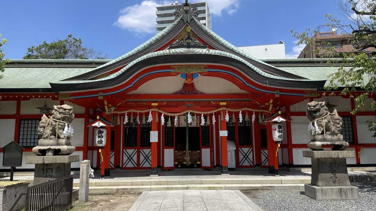 玉造稲荷神社の朱色の拝殿。左右に狛犬が並び、軒に提灯が下がっている