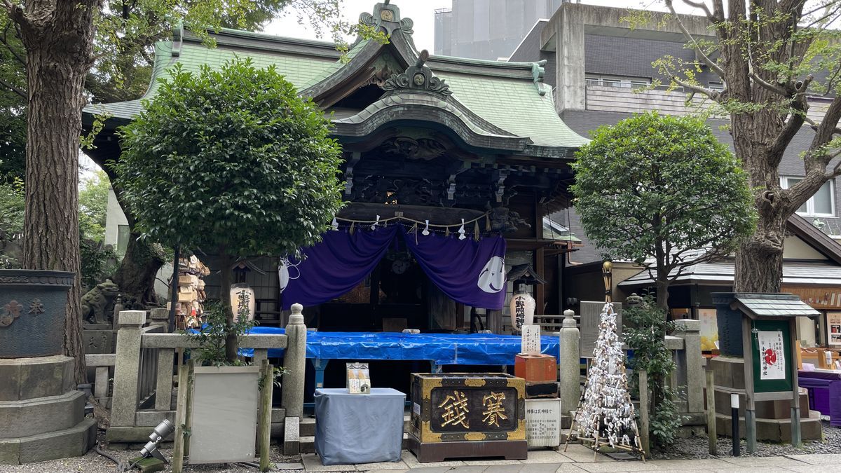 小野照崎神社の社殿。緑の屋根の下に紫の幕がかかり、手前に「賽銭」と書かれた賽銭箱がある